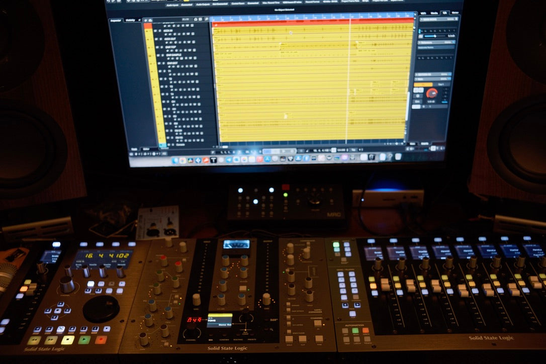 Music production setup with a mixing console and computer screen displaying audio software