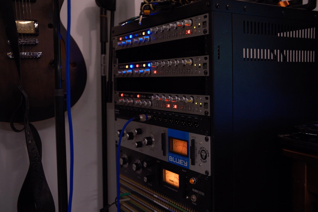 Audio equipment rack with various devices and cables in a studio setting